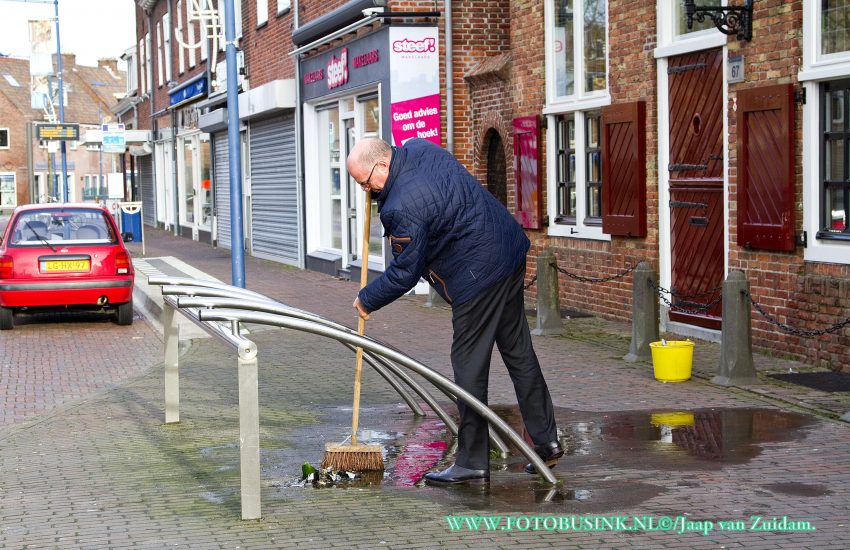 Winkelier veegt op nieuwjaarsdag de straat schoon.